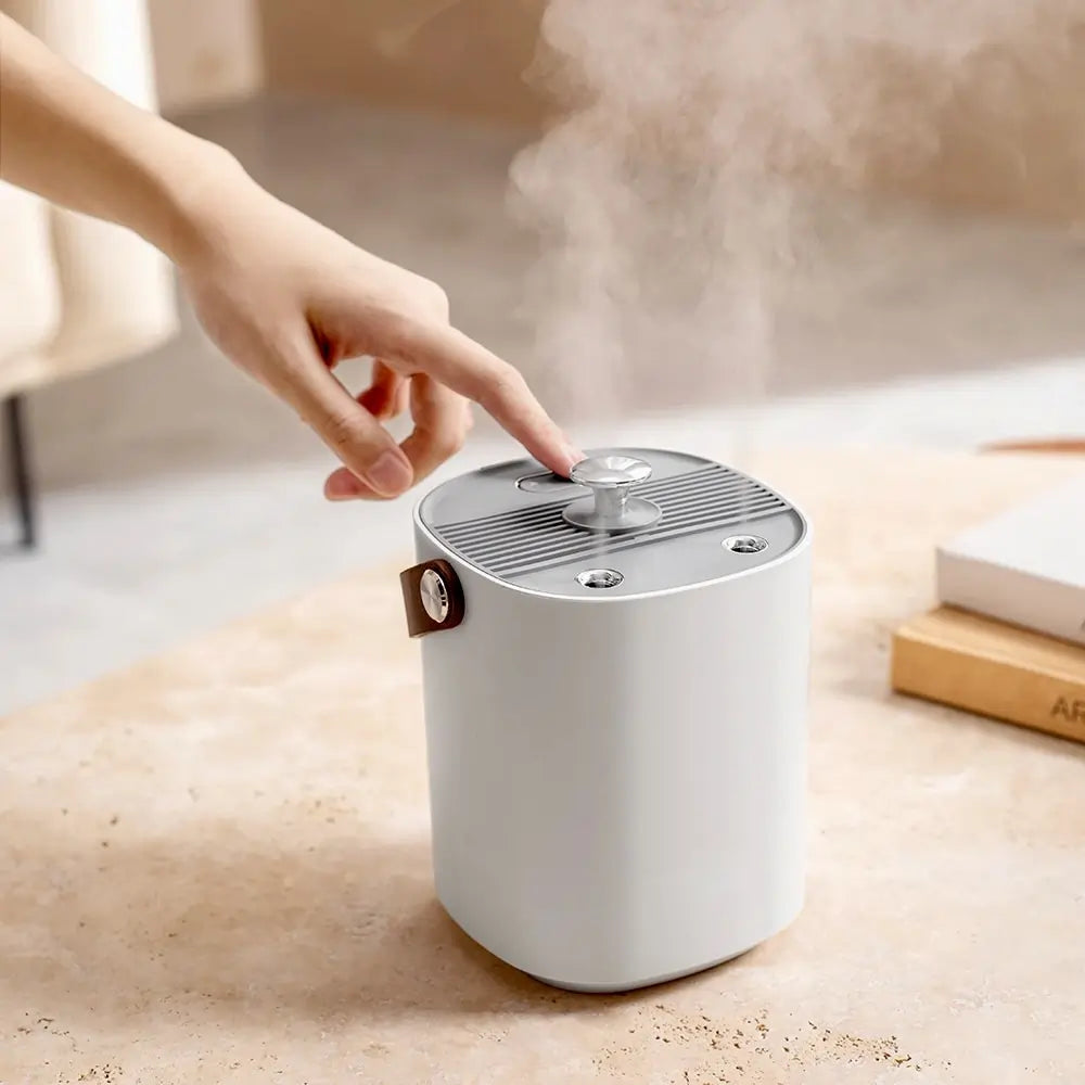 White humidifier on a wooden surface with steam rising, hand touching the top.